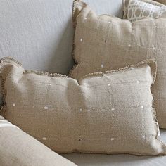 three pillows sitting on top of a white couch