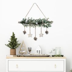 a white dresser topped with christmas decorations and greenery next to a wall mounted star ornament