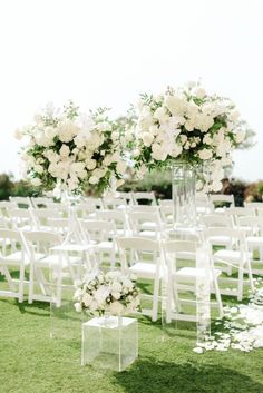 an outdoor ceremony with white flowers and clear acrylic chairs on the grass area