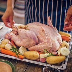 a person cutting up a large piece of chicken on top of veggies and potatoes