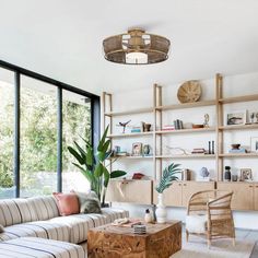 a living room filled with furniture and lots of windows next to a wooden shelf on the wall