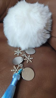 a white fur ball sitting on top of a brown leather couch with snowflakes