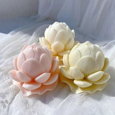 three soap flowers sitting on top of a white sheet