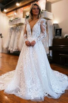 a woman in a white wedding dress standing on a wooden floor next to a piano