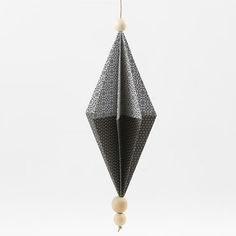 a black and white origami decoration hanging from a string with beads on it