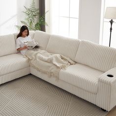 a woman sitting on a couch reading a book