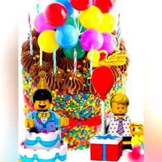 a birthday cake with legos and balloons on it's top, surrounded by other toys