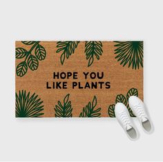 a pair of white shoes sitting on top of a door mat that says plant your feet here