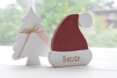 a wooden santa hat next to a small white christmas tree on a window sill