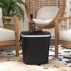 a black trash can sitting on top of a rug next to two wicker chairs