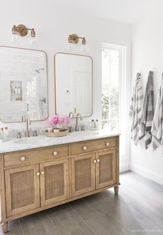 a bathroom with two sinks, mirrors and towels hanging on the wall above it's double vanity