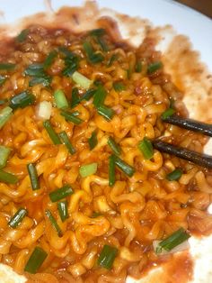 a plate full of noodles with chopsticks on the side and sauce in the middle