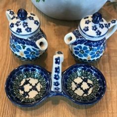 three pieces of blue and white pottery sitting on a wooden table next to a potted plant