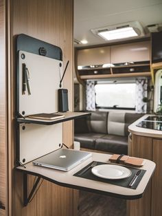 an rv kitchen with laptop, tablet and phone on the table in front of it