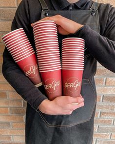 a man holding four red cups in his hands