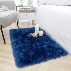 a blue shaggy rug on the floor in a bedroom next to a white chair and bed