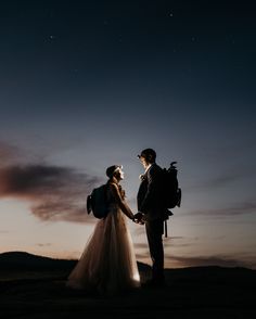 a bride and groom holding hands under the night sky