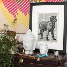 there is a lion on top of a book page next to two buddha heads and a potted plant