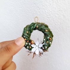 a hand is holding a christmas wreath ornament