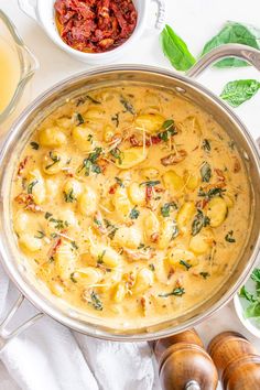 a pan filled with pasta and sauce next to other ingredients on a table top,