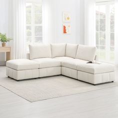 a white sectional sofa in a living room with two windows and a rug on the floor