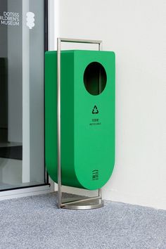 a green trash can sitting next to a glass door