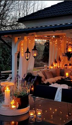 an outdoor covered patio with candles on the table and lights hanging from the ceiling above it