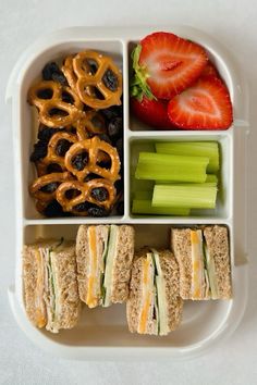 a lunch box filled with sandwiches, fruit and pretzels