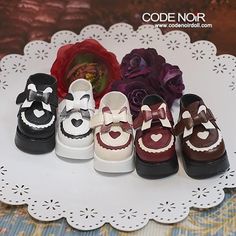 several pairs of baby shoes with hearts on them sitting on a white doily next to a flower