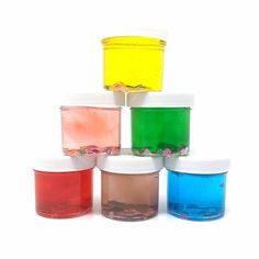 four jars with different colored liquids in them on a white surface, each containing one individual's own substance