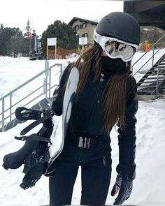 a woman with long hair holding skis in her hands and wearing a helmet on top of her head