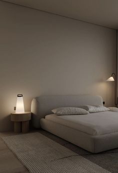 a large bed sitting next to two lamps on either side of the bed in front of a window