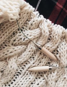 some knitting needles are laying on a blanket