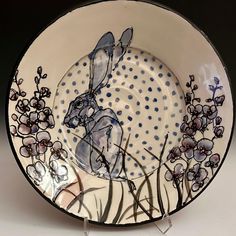 a plate with an image of a rabbit and flowers painted on the inside of it