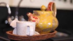 two coffee mugs sitting on top of a wooden tray next to a tea pot