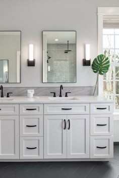 a bathroom with double sinks, mirrors and two lights on the wall next to each other