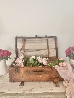 an old suitcase with flowers in it sitting on a table