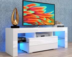 a flat screen tv sitting on top of a white entertainment center next to a blue wall