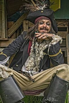 a man dressed in pirate garb sitting on the ground