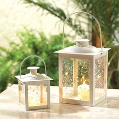 two white lanterns sitting on top of a table