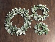 two wreaths made out of fake leaves on a wooden table next to each other