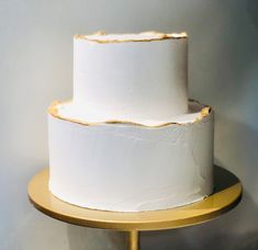 a three layer white cake on a gold stand