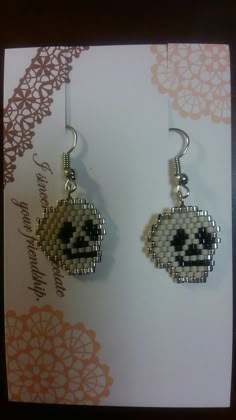 a pair of beaded earrings with a skull on it's earring hooks