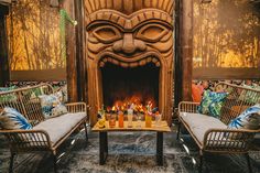 two wicker chairs sitting in front of a fire place with drinks on the table