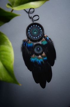 a blue and black dream catcher hanging from a tree branch