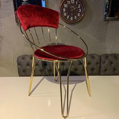 a red chair sitting on top of a white table next to a wall mounted clock