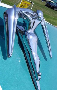 the hood ornament of an old car is shiny and chromed in color