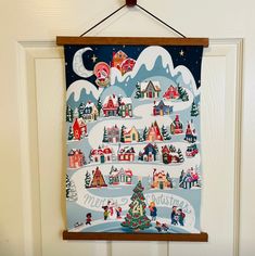 a christmas card hanging on a door with a santa's sleigh and village in the background