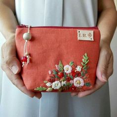 a woman holding a red purse with flowers on it