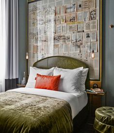 a hotel room with a bed, green velvet headboard and red pillows